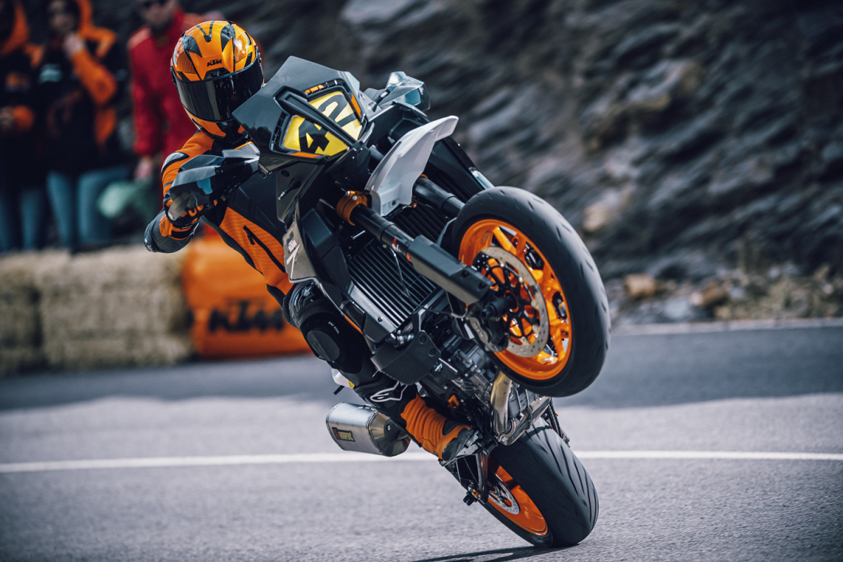 The new launched KTM 890 SMT doing a wheelie at a race event ridden by a professional rider in a full leather suit