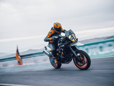 The new launched KTM 890 SMT ridden by a professional rider in a full leather suit through a racetrack in cloudy overcast weather