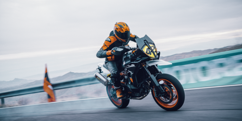 The new launched KTM 890 SMT ridden by a professional rider in a full leather suit through a racetrack in cloudy overcast weather