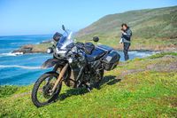 2023 Kawasaki K L R 650 Adventure parked on grassy bluff with rider standing in background